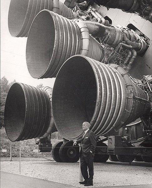 Wernher von Braun at the working end of a Saturn V rocket, with five F-1 engines, unused first stage at Marshall Space Flight Center, Huntsville, Alabama, photograph, early 1970s (Wikimedia commons)