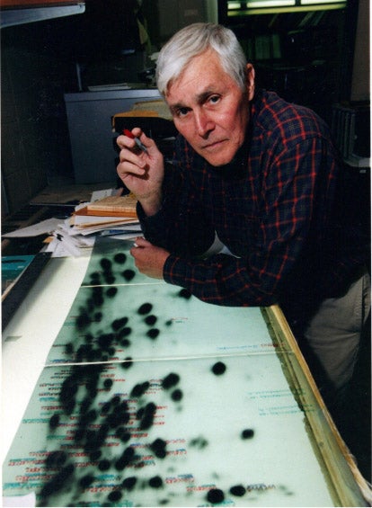 An older Carl R. Woese at his light table, with prints of electrophoretic separations of fragments of 16S ribosomal RNA, with which he discovered the existence of the Archaea domain, undated photograph, Carl R. Woese Institute for Genomic Biology, University of Illinois (www.igb.illinois.edu)