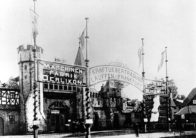 Illuminated display positioned near the entrance of the International Electrotechnical Exhibition in Frankfurt am Main. The pump-driven waterfall is visible on the right side of this photograph. (Wikimedia Commons)