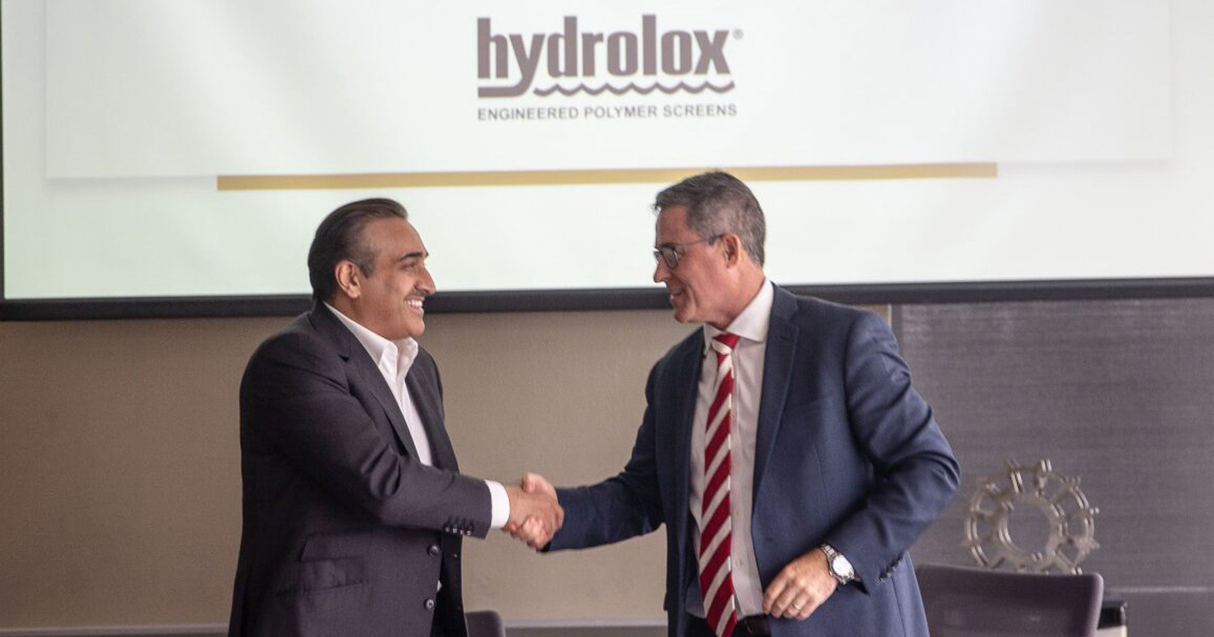 Business shanking hands in front of Hydrolox logo