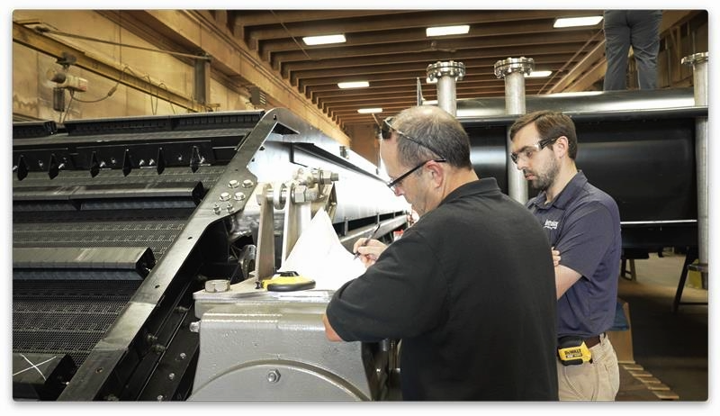 Two men examining paperwork next to Hydrolox water screen