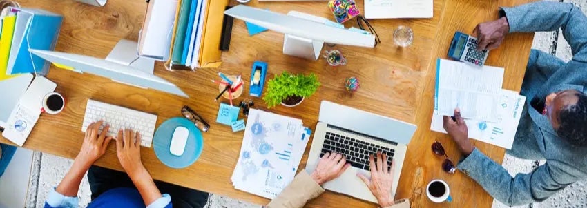 Young developers working in their start-up home office. They are brainstorming, woman holding pencil and writing while talking with her coworker. They are collaborating. Top view. Location is released.