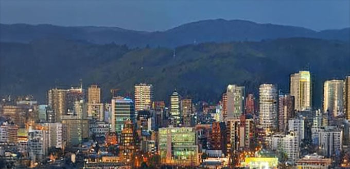 Vista nocturna de Concepción con rascacielos iluminados, centro urbano activo y cerros al fondo, Concepción, Chile.