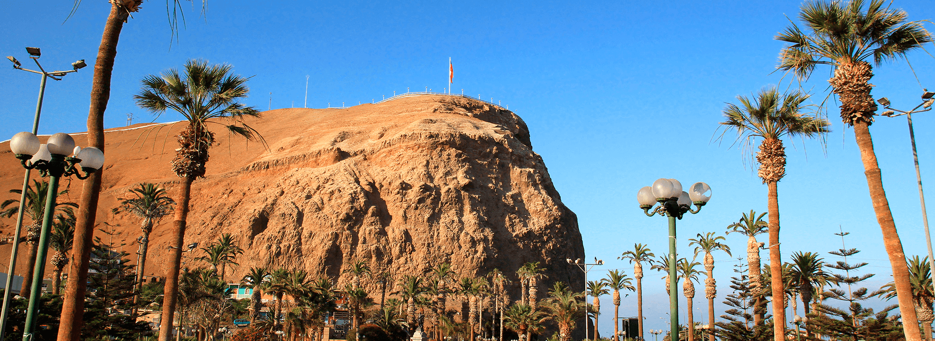Morro de Arica con palmeras y paseo urbano, ícono turístico del norte de Chile bajo cielo despejado