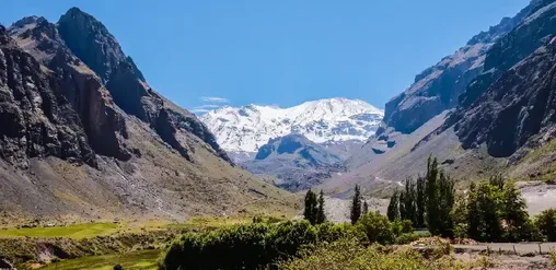 Vista del Cajón del Maipo con montañas andinas, valle verde y cumbres nevadas cerca de Santiago de Chile.