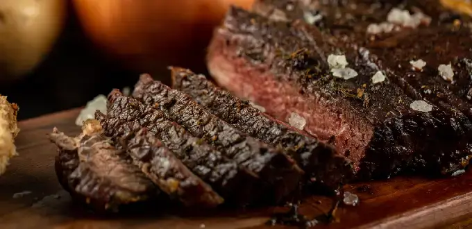 Carne asada cortada con sal gruesa, cebolla y papas, ideal para gastronomía argentina.