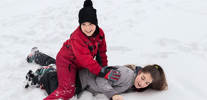 Niños jugando y riendo sobre la nieve, disfrutando actividades de invierno al aire libre en Farellones, Chile.