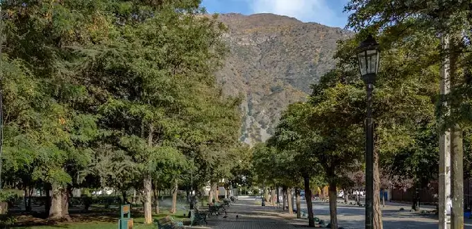 Plaza y paseo arbolado en San José de Maipo, Cajón del Maipo, con vista a montañas de la cordillera cerca de Santiago de Chile.