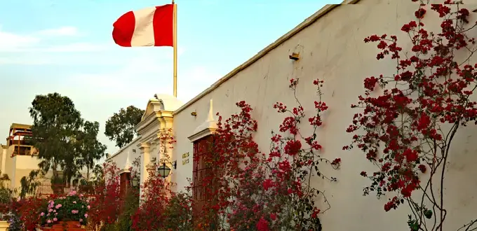Museo Larco en Lima, Perú, con fachada colonial, buganvilias y bandera peruana.