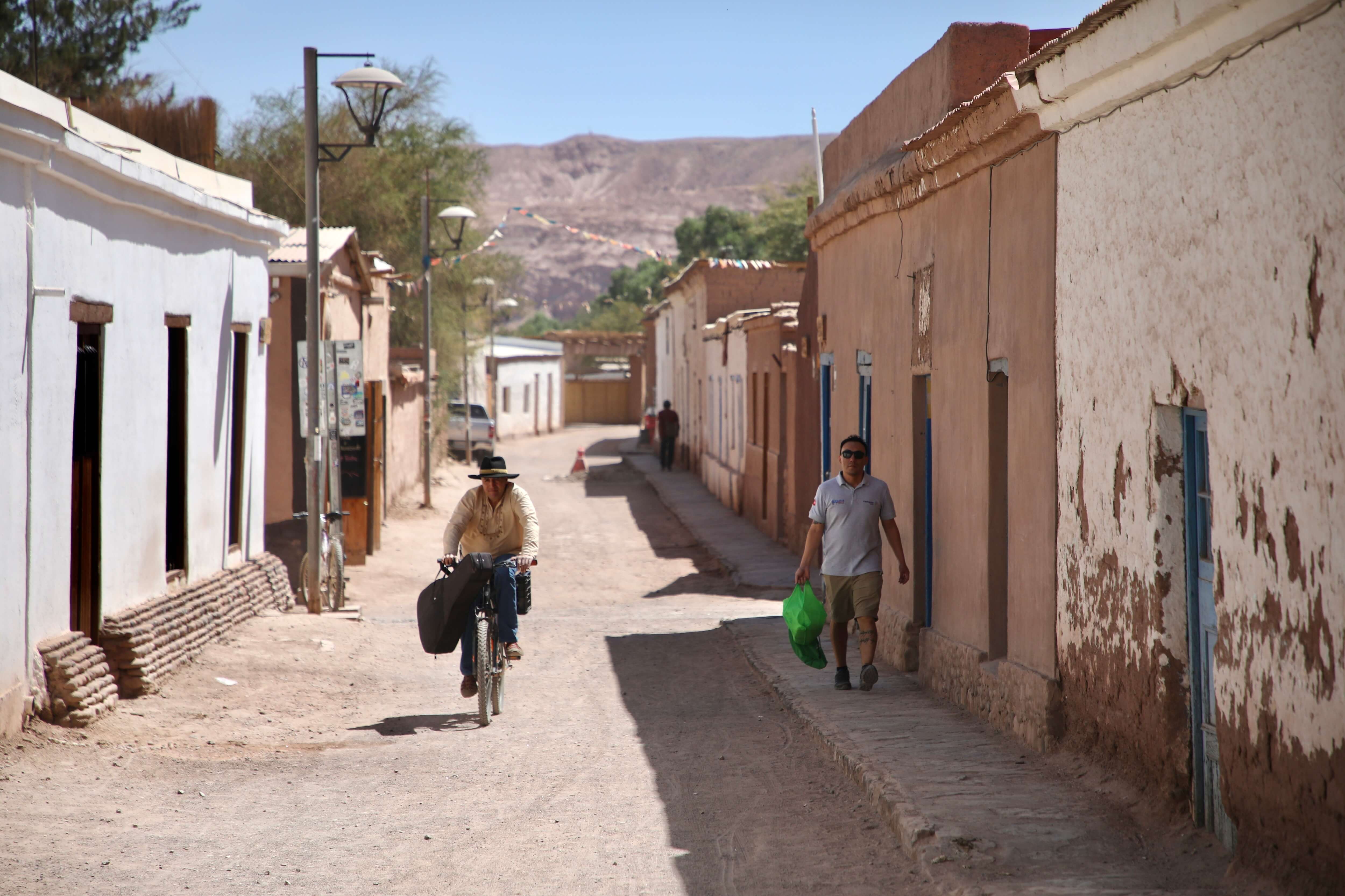 Calle de adobe con vida local en pleno desierto, arquitectura tradicional de San Pedro de Atacama, Región de Antofagasta, Chile.