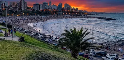 Playa Varese en Mar del Plata, Argentina, al atardecer, con amplia costa, mar y vista del skyline urbano.