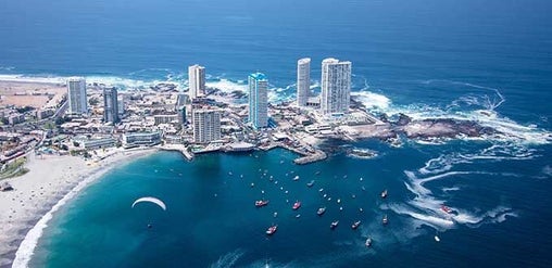 Iquique, Chile: vista aérea de bahía con edificios costeros, embarcaciones, playa urbana y océano Pacífico.