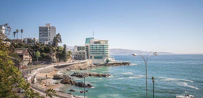 Vista costera de Avenida España con edificios, roqueríos y mar azul junto a la costa de Viña del Mar, Chile.