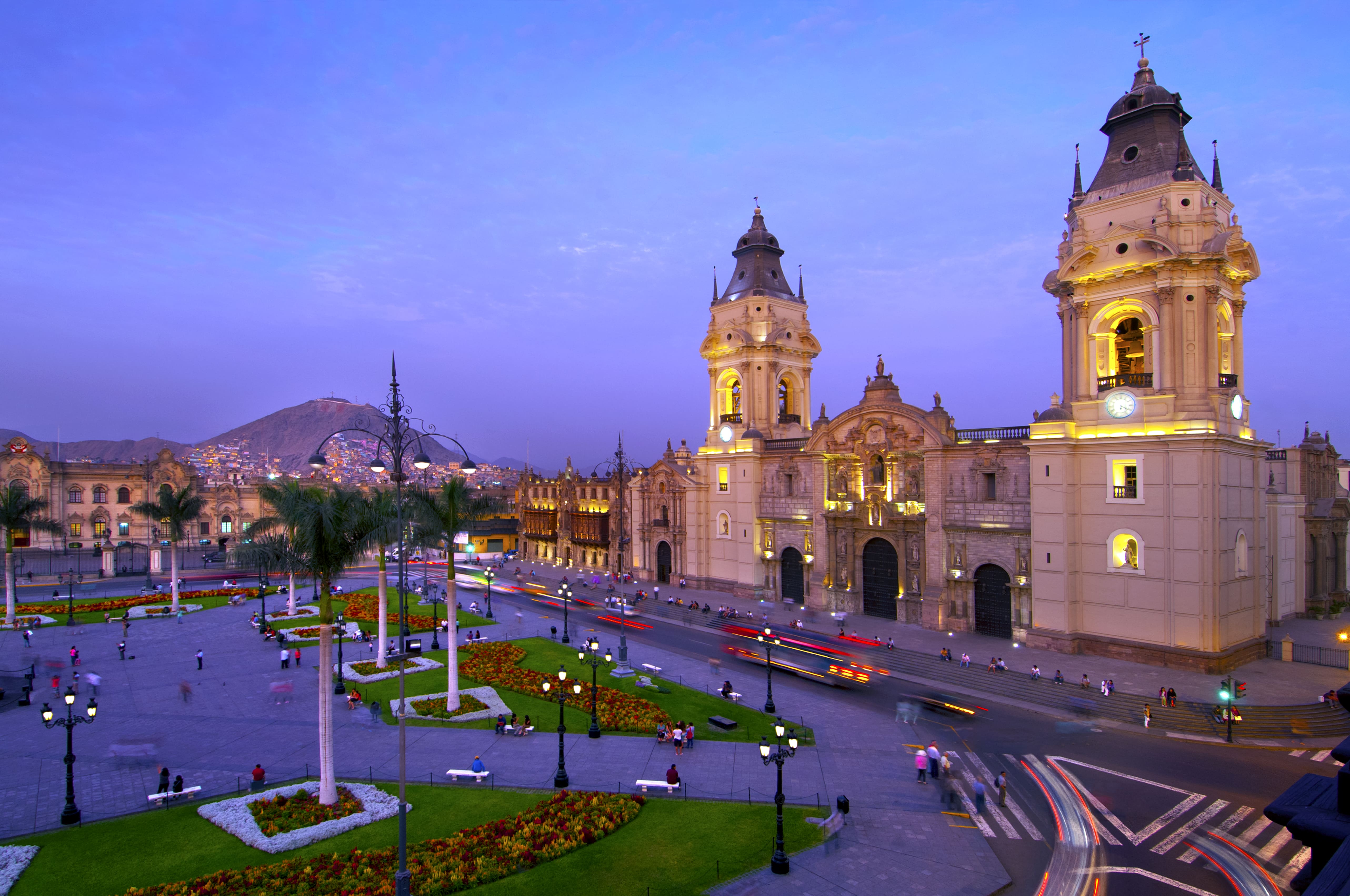 Catedral de Lima iluminada al atardecer en la Plaza Mayor, ubicada en el Centro Histórico de Lima, con el Cerro San Cristóbal al fondo.