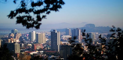 Vista urbana de Concepción con edificios modernos, áreas residenciales y cerros al fondo bajo cielo despejado, Concepción, Chile.