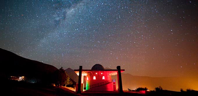 Observatorio Mamalluca, Valle del Elqui, Chile: cielo nocturno estrellado con la Vía Láctea sobre cúpula iluminada.