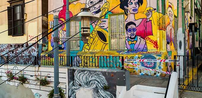 Murales de arte callejero con rostros y colores vibrantes en fachadas patrimoniales del cerro Alegre, Valparaíso, Chile.
