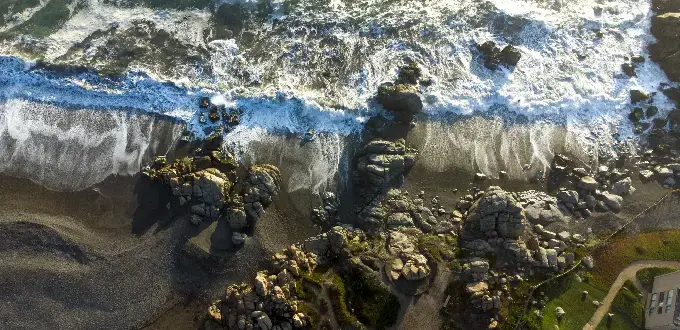 Playa rocosa en Santo Domingo, con olas rompiendo sobre la costa y senderos junto al mar.