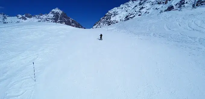 Esquiador descendiendo por pista nevada en la cordillera de los Andes cerca de Santiago, rodeado de montañas cubiertas de nieve.