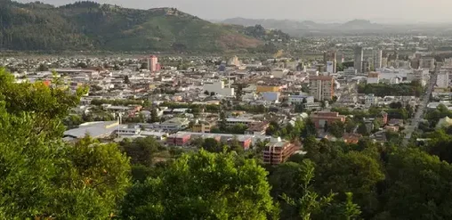 Vista panorámica de Temuco desde el Cerro Ñielol, con la ciudad rodeada de áreas verdes y cerros en la Araucanía, Chile.