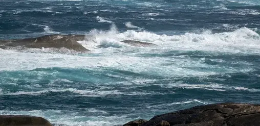 Oleaje intenso rompiendo sobre rocas en la costa del Pacífico en Isla Negra, Chile, con mar azul profundo y espuma blanca.