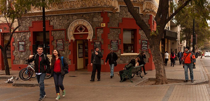 Personas caminan y se reúnen frente a locales culturales en Barrio Bellavista, zona bohemia y turística de Santiago de Chile.