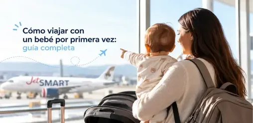 Madre con bebé y equipaje observa un avión JetSMART desde el aeropuerto, preparándose para su primer viaje en familia.