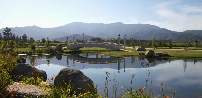 Laguna con puente y jardines en Estancia El Cuadro, Valle de Casablanca, Chile, rodeada de viñedos y montañas.