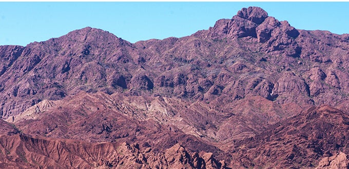 Formaciones rocosas rojizas y montañas erosionadas del Valle Calchaquí en Salta, destacando paisajes áridos y geografía andina.
