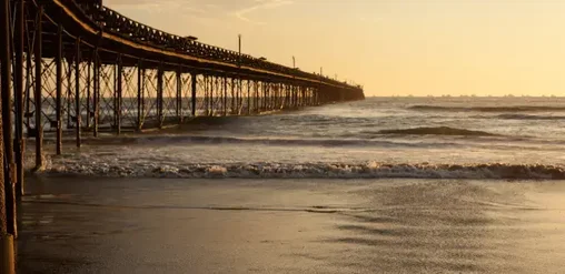 Muelle histórico de Pimentel en Chiclayo, Perú, con vista al océano Pacífico durante el atardecer.