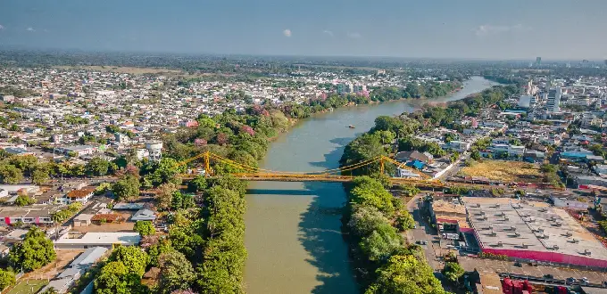 Vista aérea de Montería, Colombia, atravesada por el río Sinú, con puentes, zonas verdes y paisaje urbano.