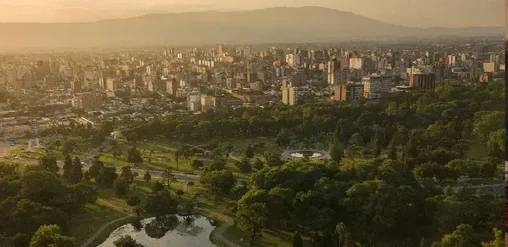 Vista panorámica de San Miguel de Tucumán, Argentina, con parques, edificios y sierras al fondo.