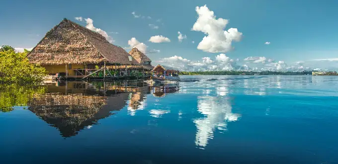 Casa flotante sobre el río Amazonas cerca de Iquitos, Perú, rodeada de selva y aguas tranquilas.
