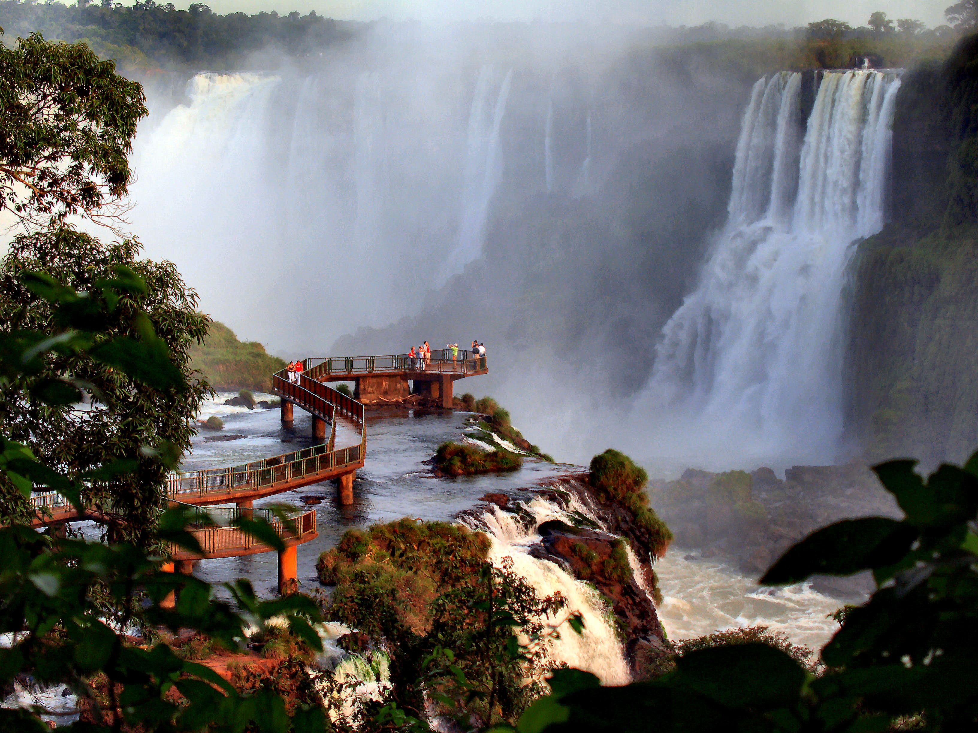 Mirador sobre las cataratas de Foz de Iguazú en Brasil, rodeado de vegetación y niebla del salto de agua.