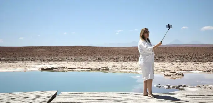 Turista tomando fotos junto a una laguna del desierto, paisaje árido de San Pedro de Atacama, Región de Antofagasta, Chile.