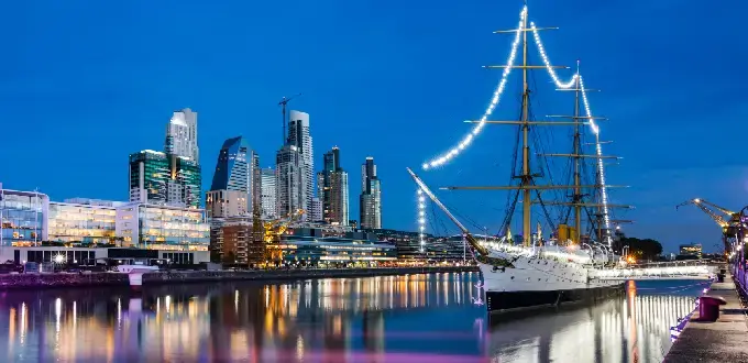 Puerto Madero de noche con skyline, río y fragata iluminada en Buenos Aires