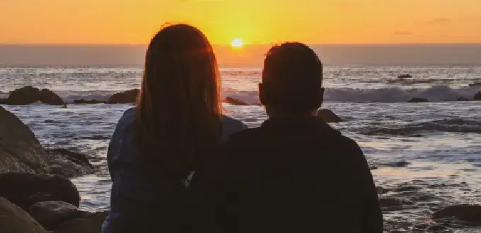 Pareja observando el atardecer frente al mar en El Quisco, balneario de la Región de Valparaíso, Chile.