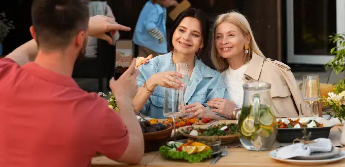 Amigas posan para una foto en restaurante de Ñuñoa, Santiago, disfrutando comida y vino en una terraza gastronómica.