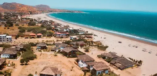 Playa de Máncora en Piura, Perú, con costa del Pacífico, arena clara y paisaje costero desde una vista aérea.