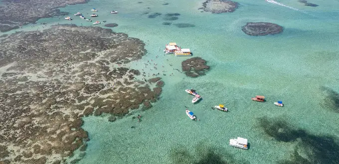 Piscinas naturales de Maragogi, Brasil, con aguas cristalinas, arrecifes de coral y embarcaciones turísticas.