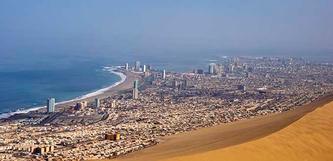 Iquique, Chile: vista panorámica desde las dunas con ciudad costera, playa urbana y océano Pacífico al fondo.