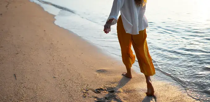 Mujer caminando por la orilla del mar al atardecer en una playa de Maitencillo, costa central de Chile.