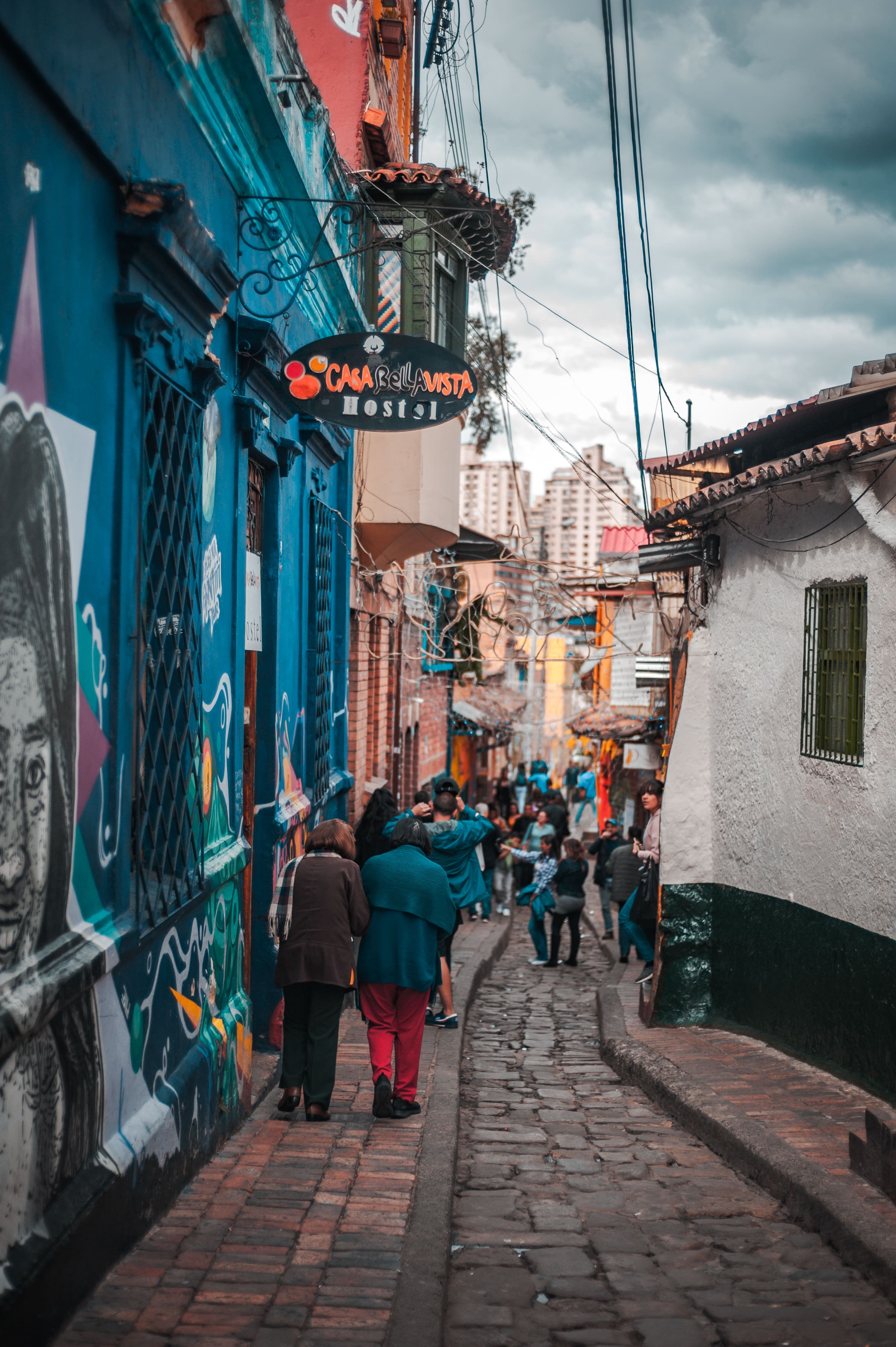 Calle turística de La Candelaria en Bogotá, Colombia, con arte urbano, transeúntes y hostal Casa Bellavista.
