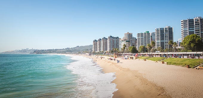 Playa El Sol con arena dorada, mar tranquilo y edificios frente a la costa en Viña del Mar, Chile.