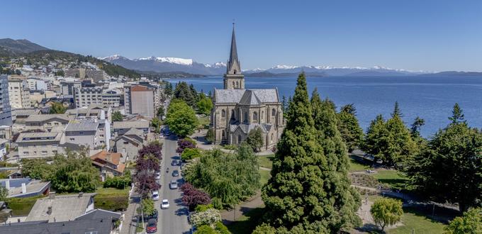 Catedral de Bariloche con vista al lago y montañas al fondo, en un día despejado.