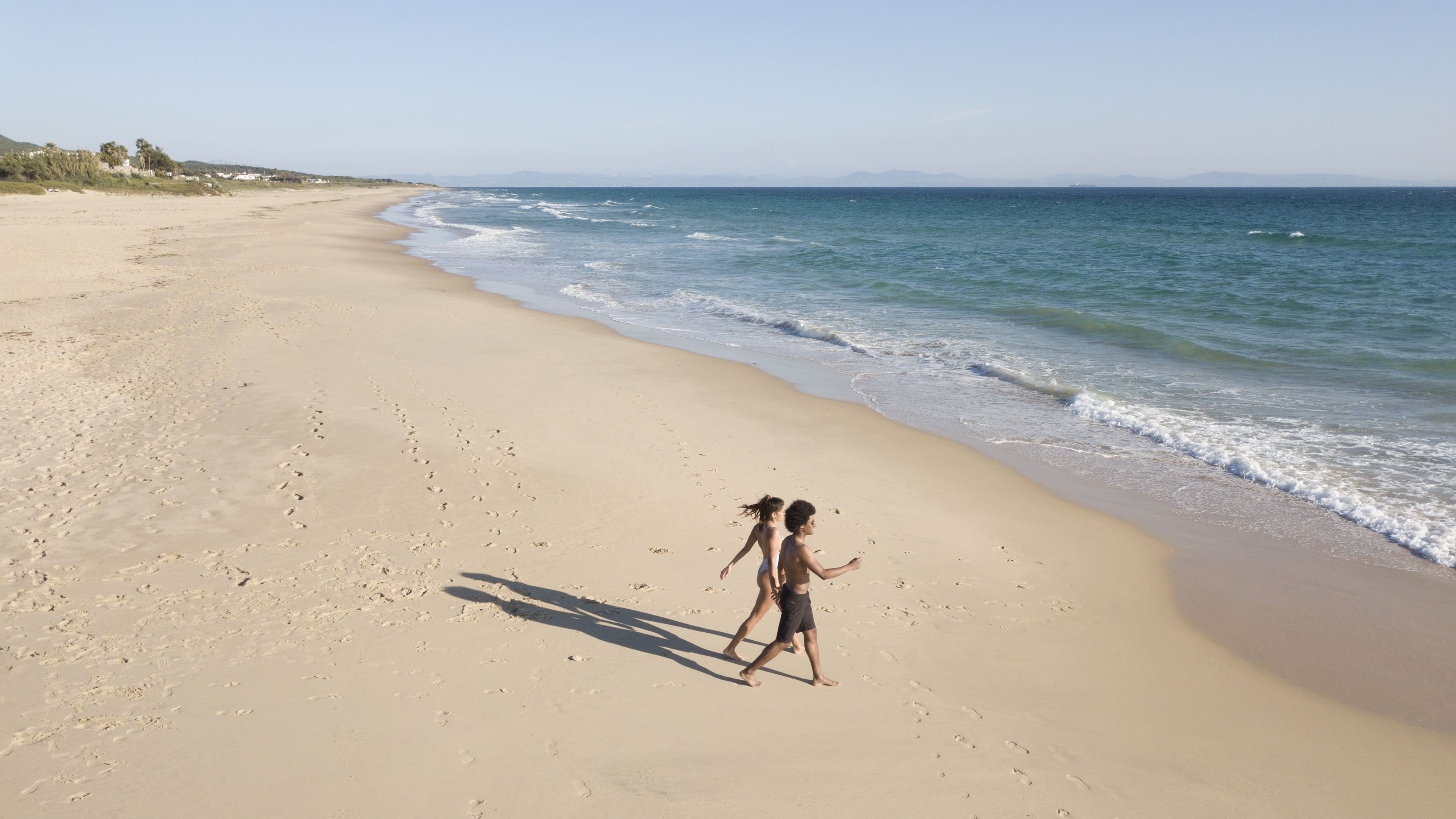 Pareja caminando por una extensa playa de arena en Pinamar, Argentina, junto al mar