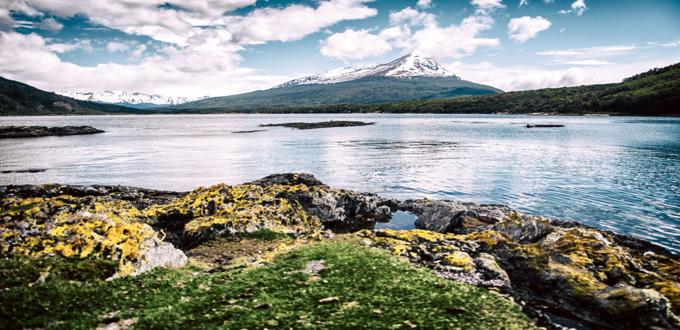 Paisaje del Canal Beagle en Ushuaia con montañas nevadas y aguas cristalinas bajo un cielo azul.