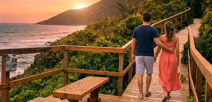 Sendero costero en Florianópolis, Brasil, con naturaleza tropical, vista al mar y viajeros disfrutando el paisaje al atardecer.