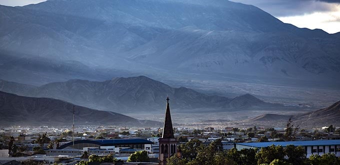 Calama, Chile: vista urbana con iglesia y ciudad al pie de cerros áridos del desierto de Atacama bajo luz suave.