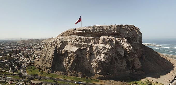 El Morro de Arica con la bandera chilena en la cima, acantilado histórico junto al océano Pacífico, Arica, Chile.
